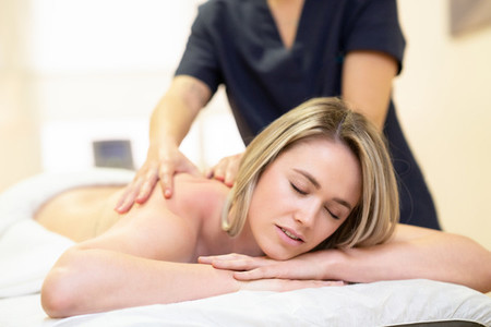 Woman lying on a stretcher receiving a back massage