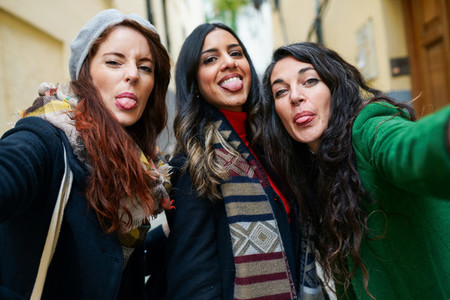 Group of woman taking a selfie photo sticking out their tongues