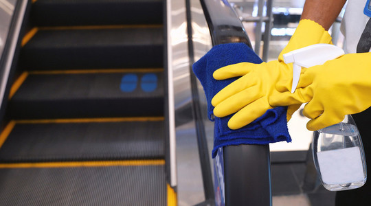 Staff cleaning the escalator hand rail in department store to pr