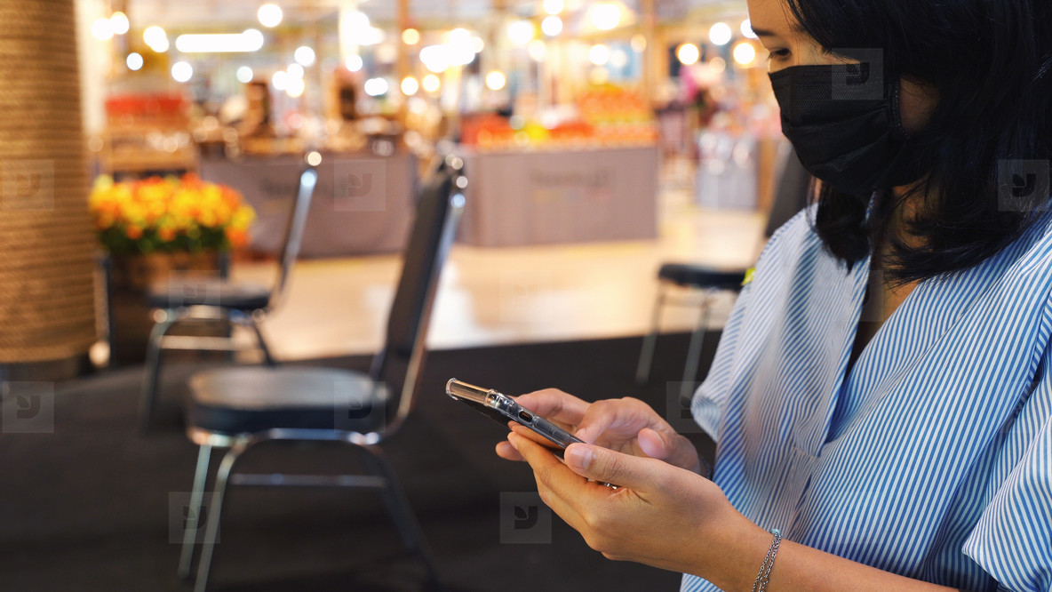 Asian woman using smartphone and sitting separated chair in shop