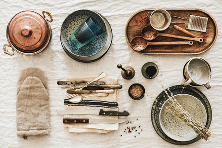 Various kitchen utensils and tablewear over rustic linen tablecloth