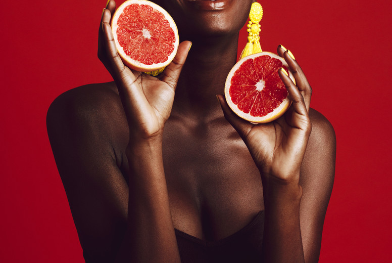 Smiling african female model holding grapefruit