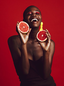 Smiling african female model holding grapefruit
