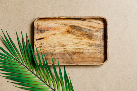 Top view of an empty wooden tray decorated palm leaf