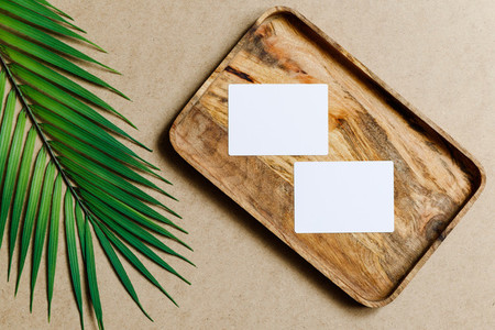 Top view of two blank paper sheet cards on a wooden tray with palm leaf  Tropic mockup for business template  copy space