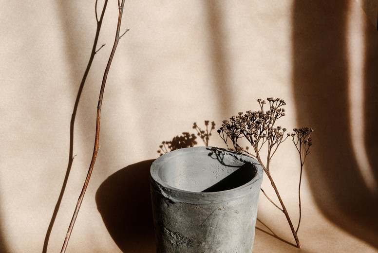 Abstract creative minimal composition with a clay pot and dry grass against kraft paper. Natural and ecological products concept.