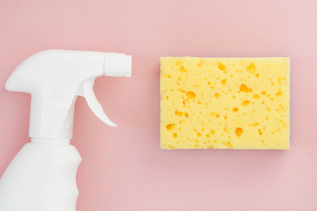 White spray and yellow sponge for washing dishes on a pink background  Copy space  Cleaning concept