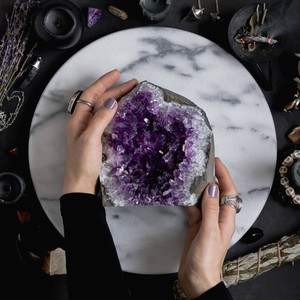 The witch is holding amethyst stone surrounded magic things  View from above
