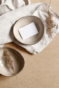 Blank paper sheet card in a bowl  Minimalist ceramics set over a linen cloth  Business template  copy space  flat lay