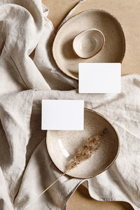 Blank paper sheet cards on bowls Minimalist ceramics set over a linen cloth Business template copy space flat lay