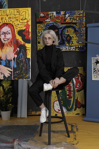Portrait confident young female artist in studio with paintings