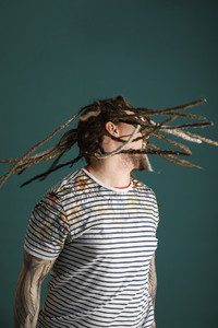 Man with dreadlocks and tattoos flipping hair