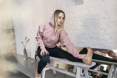 Young woman stretching leg in yoga studio