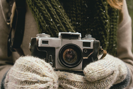 Close up woman in mittens holding retro camera