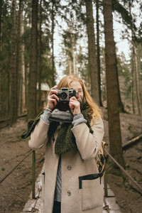 Portrait woman using retro camera in woods