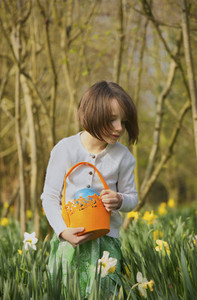 Girl with Easter egg basket in field of daffodils