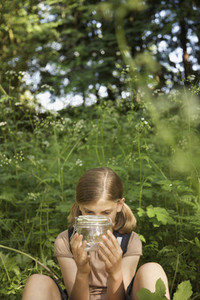 Curious girl with insect jar in woods