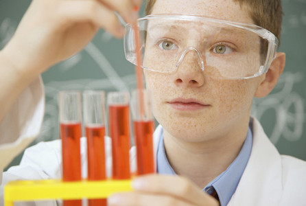 Curious junior high school boy examining liquid in science test tubes