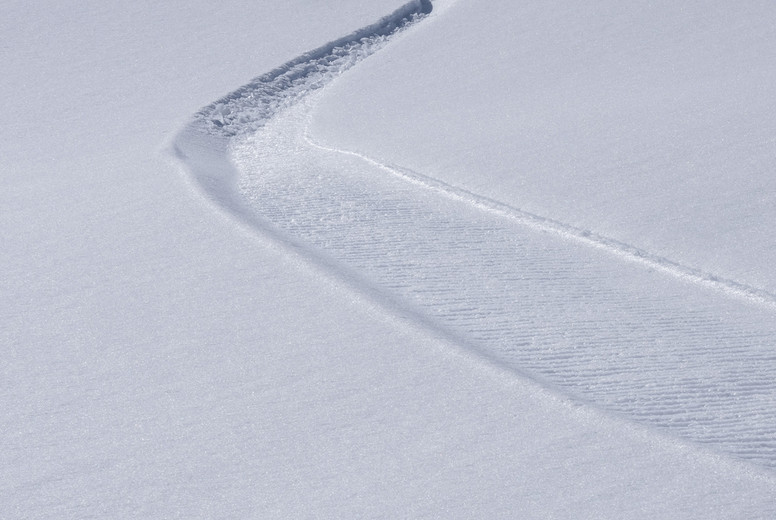 Winding path on sunny snowy slope