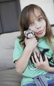 Portrait silly girl holding baby ferret and making a face