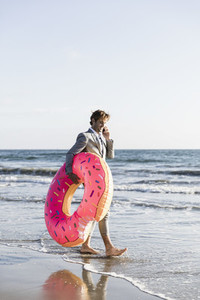 Businessman with inflatable donut on sunny ocean beach
