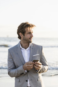 Businessman with smart phone on ocean beach