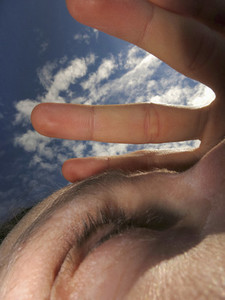 Close up woman shielding eyes with hand under sunny sky