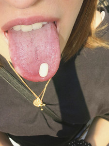 Close up woman with pill on tongue