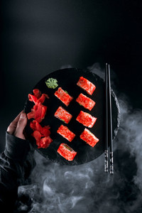 sushi california on a black stone board on a background of smoke