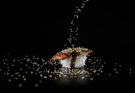 sushi with sesame seeds on black background