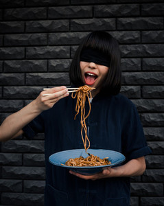 the girl with a blindfold eats east noodles