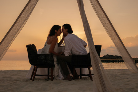 Romantic couple kissing at sunset dinner
