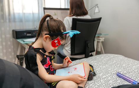 Girl drawing in disguise while her mother teleworking