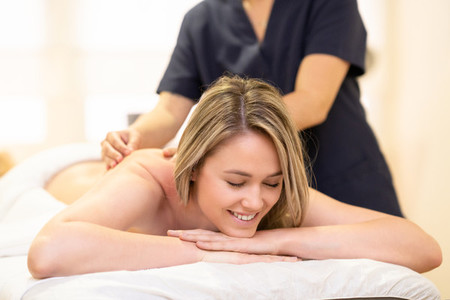 Woman lying on a stretcher receiving a back massage