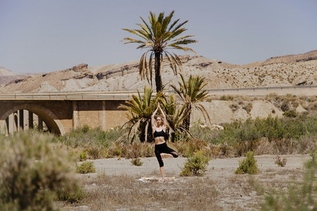 Young active woman practicing yoga in desert on sunny day  health and active life concept
