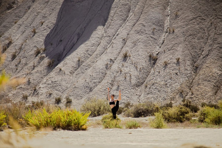 Young active woman practicing yoga in desert on sunny day health and active life concept