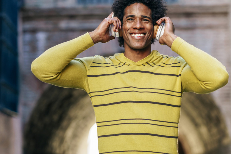 Black man listening to music with wireless headphones sightseeing in Granada