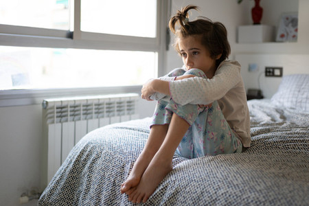Nine year old girl sitting in bed bored by confinement