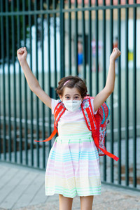 Girl wearing a mask takes a jump for joy at going back to school