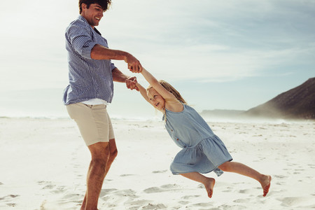 Father playing with his daughter on beach vacation
