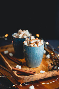 Hot chocolate with marshmallows and cinnamon in blue ceramic cups on a table  The concept of cozy holidays and New Year