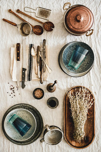 Various kitchen utensils and tablewear over linen tablecloth  vertical composition