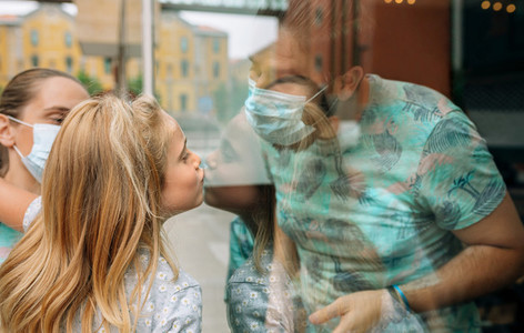 Girl giving a kiss through the glass to her father