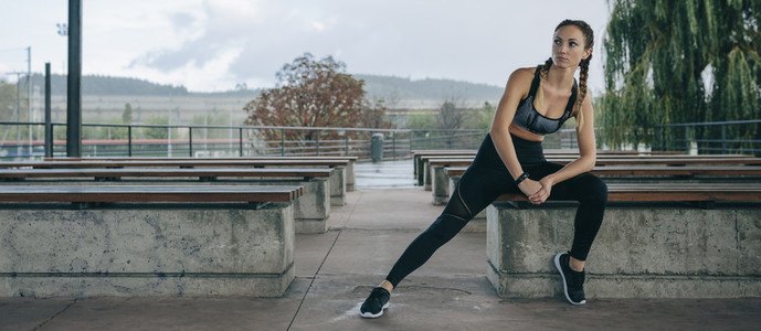 Sportswoman posing sitting on a bench