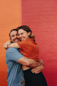 Loving couple embracing against colored wall