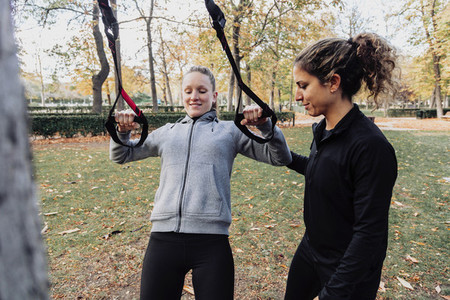 Women training with trx outside in the park