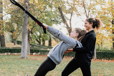 Women training with trx outside in the park
