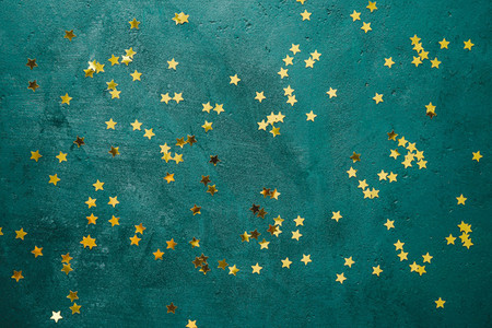 The New Year or Christmas festive flat lay with golden stars over a dark green background Top view