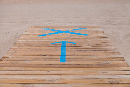 Symbol of an arrow on the wooden walkway in indicating the entrance to the beach