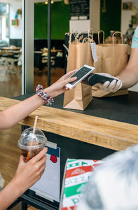 Unrecognizable woman paying with mobile a take away order